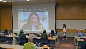 Anita Savo's image, on projection screen, with in-person audience facing screen.